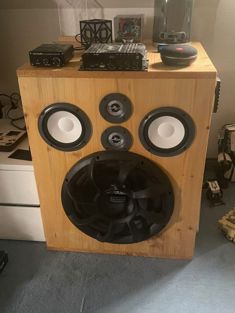 Holzlautsprecher mit großen Lautsprechern und zusätzlichen Geräten darauf.